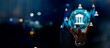 © Zerofukuman - Businessman holding digital bank icon with financial data interface, concept of online banking service,digital payments,online transactions,secure money transfer,financial technology in global economy