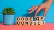 © Navee - Hand arranging code of conduct blocks on desk representing ethics rules and corporate compliance concept