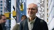 © DC Studio - Street portrait of elderly male business professional with glasses among urban crowd, highlighting movement, activity and diverse pedestrians in a busy downtown cityscape. Retirement age. Camera B.
