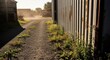 © Budi - Rustic gravel driveway with scattered weeds leading to a weathered industrial building