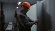 © Framestock - Male Industrial Worker Unlocks Metal Cabinet, Checks Wristwatch, and Removes Hard Hat, Changing Clothes While Friendly Interacting With Coworkers in Modern Locker Room. Professional Factory Routine.
