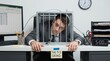 © Alveena - Businessman trapped in metal cage on office desk with 9 5 grind sign