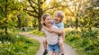 © Linklunk - Heartwarming portrait of a happy older sister giving her little brother a piggyback ride in a sunny park