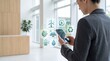 © Emily - Businesswoman using smartphone with sustainable energy icons, renewable power management app interface, green technology concept for corporate environmental strategy and