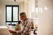 © Marko Geber - Older man reviewing bills while drinking coffee in home kitchen