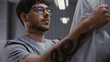 © Framestock - Close Up of Young Male Doctor in Glasses, Removes Protective Mask, Rubs Eyes From Fatigue, and Takes Off White Medical Coat in Hospital Locker Room. Concept of Exhaustion and Hard Work in Healthcare.