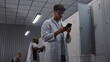 © Framestock - Young Male Doctor in White Coat Takes Smartphone From Metal Locker and Checks Messages, While Colleagues Undress After Medical Shift in Clinic Locker Room. Concept of Healthcare Communication.