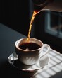 © The Little Hut - Close-up of hot coffee being poured into a white cup and saucer with dramatic sunlight and shadow patterns