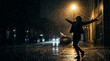 © PrusarooYakk - A silhouette of a person joyfully dancing in the rain on a dimly lit street at night, with wet pavement reflecting the streetlights.