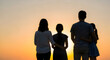 © Sharmin - silhouette of three people standing together at sunset with warm golden backlight creating unity and teamwork concept
