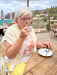 © luciano - Senior Woman Drinking Coffee at Outdoor Seaside Cafe on a Relaxing Vacation Morning