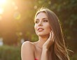 © udan - A woman with long hair touching her face outdoors