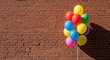 © Sulistiyono - Colorful bunch of balloons against brick wall