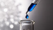 © Alex & M Studio - Macro shot of a glass dropper releasing a single drop of concentrated blue liquid into a glass vial against a bright white glowing bokeh background representing science or skincare