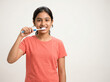 © Someone Cooked Here - indian teenage girl brushing teeth with toothbrush isolated on soft off white background representing dental care and personal hygiene concept
