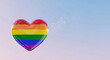 © PhotoArtHub - A glossy heart with rainbow stripes against a soft, gradient sky, symbolizing pride and inclusion with subtle sparkling light effects