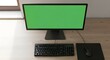 © Arsin Siregar S.IP - Top-down view of a modern computer workstation with a green screen monitor, black keyboard, and mouse on a wooden desk near a window.