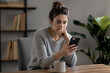© Giovanna - Woman reading message on smartphone with worried expression, thinking before replying, communication and relationship tension concept