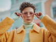 © Alper - Young woman with curly hair adjusts her pink tinted glasses, wearing a fluffy yellow coat