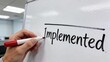 © Husen - A hand writes Implemented on a whiteboard with a red marker in an office.