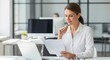 © twilight mist - Professional woman sitting at a desk and reviewing documents in a modern office environment.