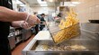 © Stitch - Fast food worker lifting a wire basket full of hot french fries out of a deep fryer