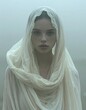 © Ka - A woman in a white headscarf and gown standing in fog