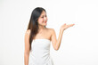 © waragron - A young woman in a white dress stands against a plain background, smiling and gesturing with her right hand as if presenting something.
