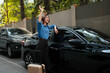 © Parichat - Woman waving hand next to car with luggage