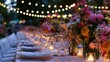 © mashimara - Elegant outdoor dinner party table setting with string lights and floral arrangements