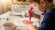 © Nurulstudio - Child carefully decorating a circular cookie with pink icing