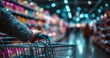 © Alexei - Hand of a shopper holding a shopping cart in a brightly lit grocery store aisle filled with colorful products and blurred background shoppers