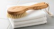 © Iqbal - Hand-carved natural bristle bath brush resting on folded white towels, offering a luxurious cleansing experience