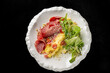 © pavel siamionov - Gourmet omelet served with salami, cherry tomatoes, and a fresh green salad on a textured white plate. Dark background, professional food photography for restaurant menu and culinary concepts