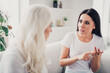 © deagreez - Young woman having a serious conversation with an older woman on a sofa, emotional disagreement and concerned discussion in a bright living room
