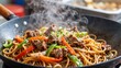 © mihrzn - Hot steaming beef and vegetable stir-fry in a wok, featuring colorful peppers, onions, sesame seeds, noodles. Traditional Asian street food.