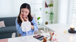 © snowing12 - young Asian woman applying makeup using lighted mirror table at home living room modern beauty routine skincare cosmetic product morning preparation lifestyle