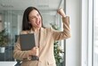 © Asier - Happy businesswoman holding a laptop, raising fist, and cheering, showing achievement and victory