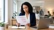 © Wattana - A woman in a suit reading a document in an office setting.