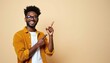 © miss irine - Young man points to empty space with happy smile. He wears glasses and an orange shirt. Man looks confident and cheerful. Use for ads or promotions.