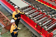 © AU USAnakul - Caucasian man uses tablet for metal sheet inspection during factory quality control assessment, conveying detailed process observation and professional focus in metal sheet factory.