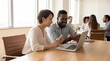 © Fridocha - Diverse Team Collaborating on Laptop in Bright Conference Room.