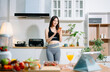 © Nuttapong punna - Fit woman using smartphone in healthy kitchen, fitness and nutrition lifestyle, meal planning, workout routine, clean eating, wellness