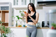 © Nuttapong punna - Fit woman using smartphone in healthy kitchen, fitness and nutrition lifestyle, meal planning, workout routine, clean eating, wellness