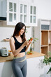 © Nuttapong punna - Fit woman using smartphone in healthy kitchen, fitness and nutrition lifestyle, meal planning, workout routine, clean eating, wellness