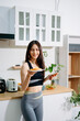 © Nuttapong punna - Fit woman using smartphone in healthy kitchen, fitness and nutrition lifestyle, meal planning, workout routine, clean eating, wellness
