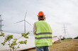 © Westend61 - Engineer with reflective jacket standing near turbine blade at field