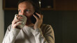 © Bits and Splits - Woman drinking coffee and talking on phone in kitchen during quiet morning moment