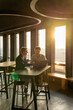 © Westend61 - Two men having a business meeting in an office at sunset with coffee and a laptop