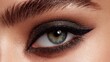 © Nurul - Close-up of a woman's eye showcasing dark smoky eyeshadow, a sharp winged liner, and well-groomed, glossy eyebrows. The eye is a vibrant blue-green